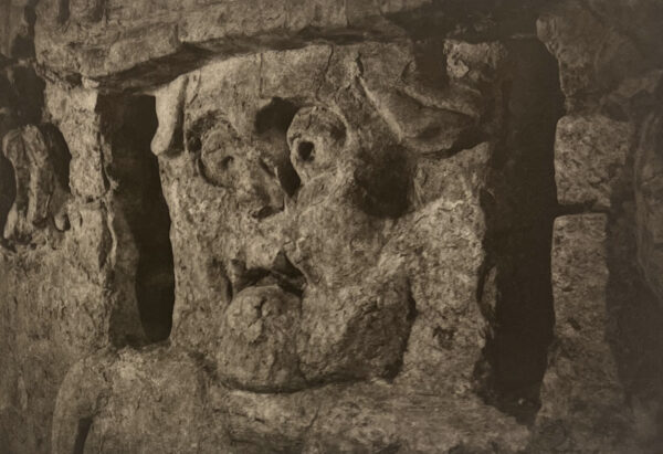 A stone carving of a face in the middle of a wall.