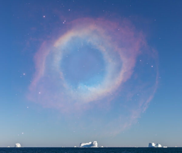 A rainbow in the sky over an ocean.