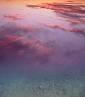 A pink sky with clouds and water