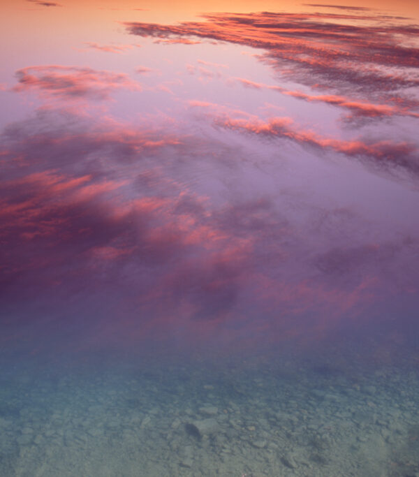 A pink sky with clouds and water