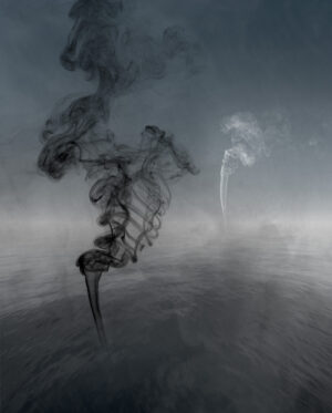 Smoke billows from a pipe in the middle of an empty field.