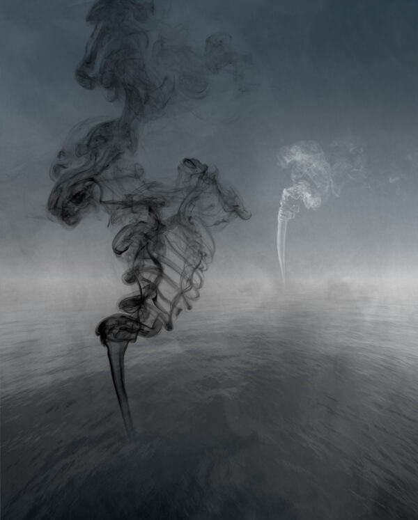 Smoke billows from a pipe in the middle of an empty field.