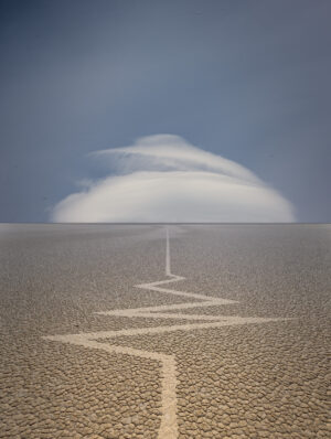 A cloud is seen in the distance behind a desert.
