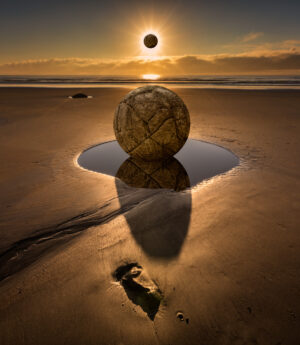 A ball on the beach with an eclipse in the background.