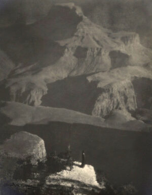 A black and white photo of two people standing on top of a mountain.