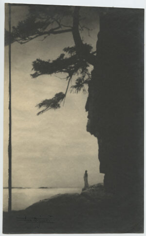 A person standing on the beach near a cliff.