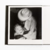 A black and white photo of a child holding another child.
