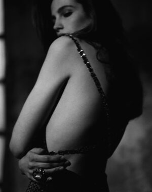 A woman in a black bikini standing next to a window.