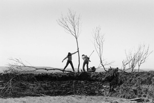 Two people standing on a hill with trees in the background