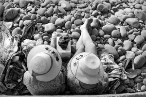 Two people laying on the ground with hats