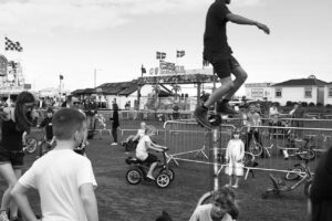 A man on a skateboard jumping over a pole.