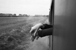 A person 's hand is seen through the window of a train.