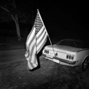 A car parked on the side of the road with an american flag.