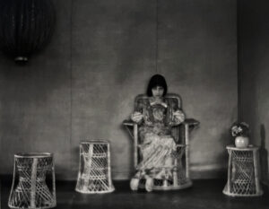 A woman sitting in a chair with two baskets on the floor.
