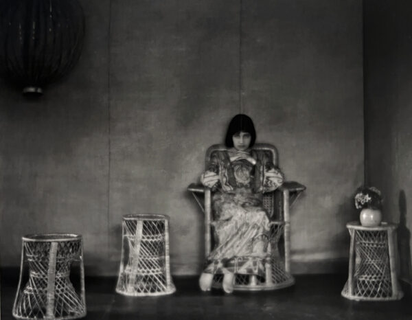 A woman sitting in a chair with two baskets on the floor.