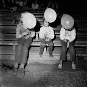Three people sitting on a bench with balloons