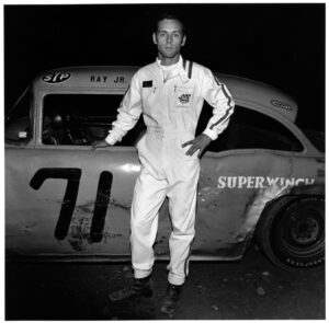 A man standing in front of an old race car.