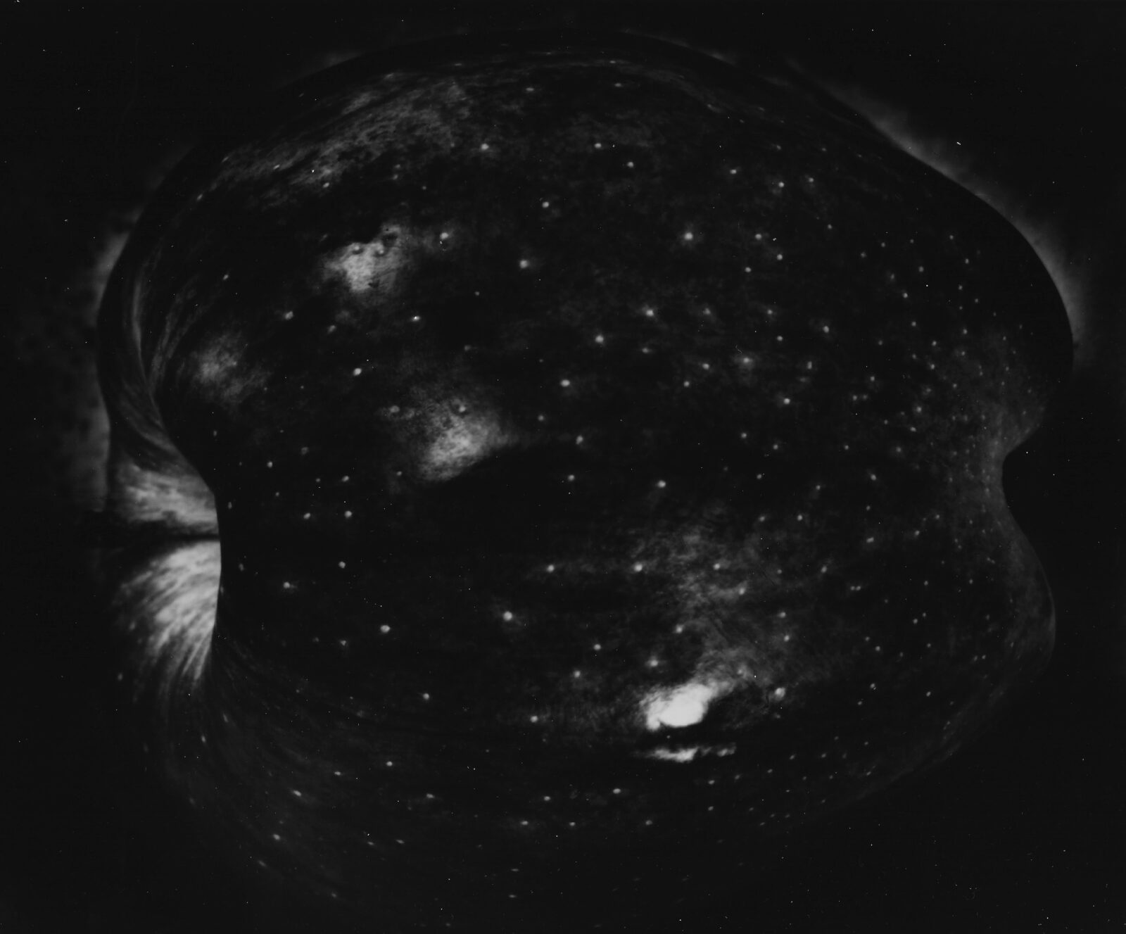 A woman and man sitting on the ground in front of a bench.