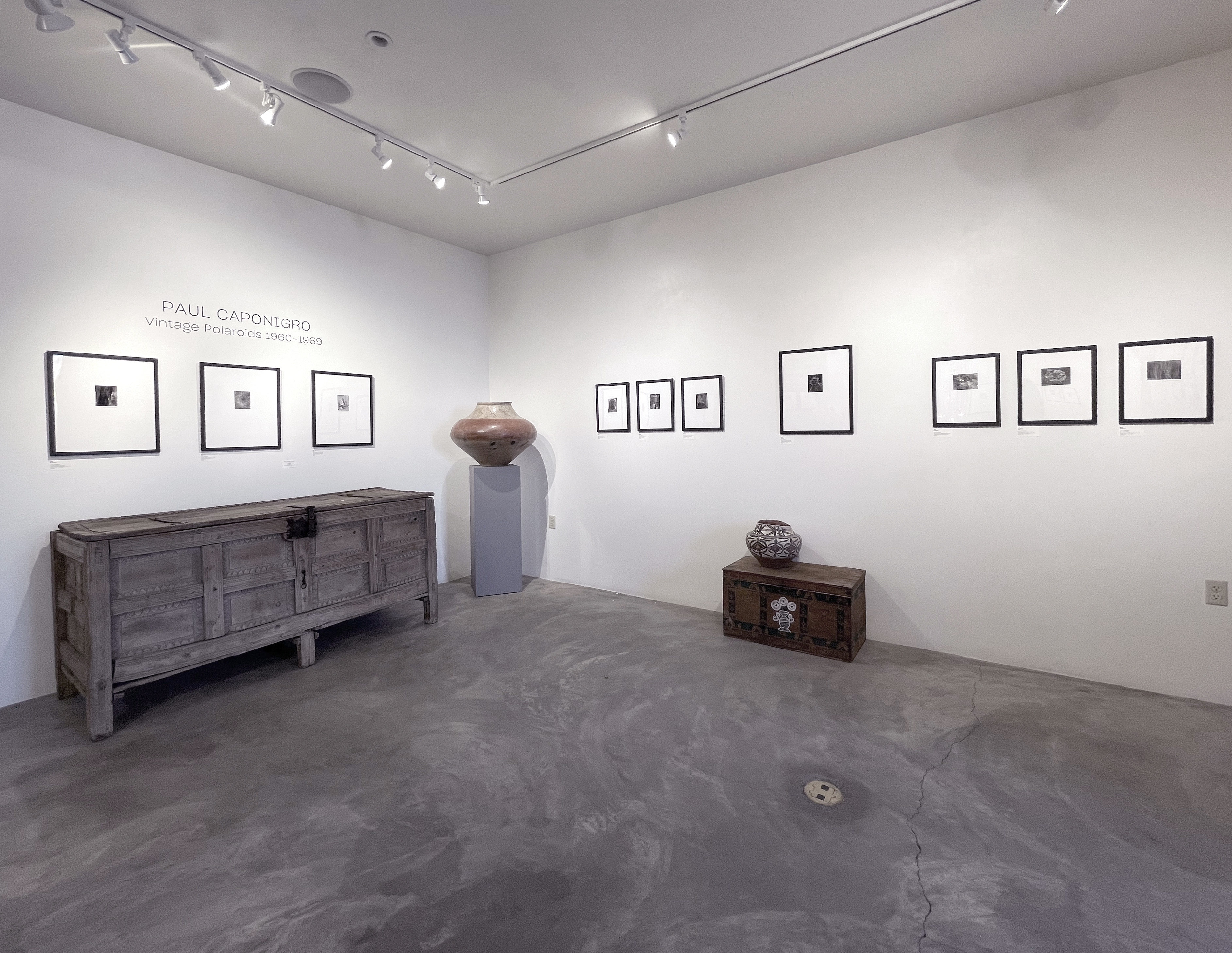 A woman and man sitting on the ground in front of a bench.