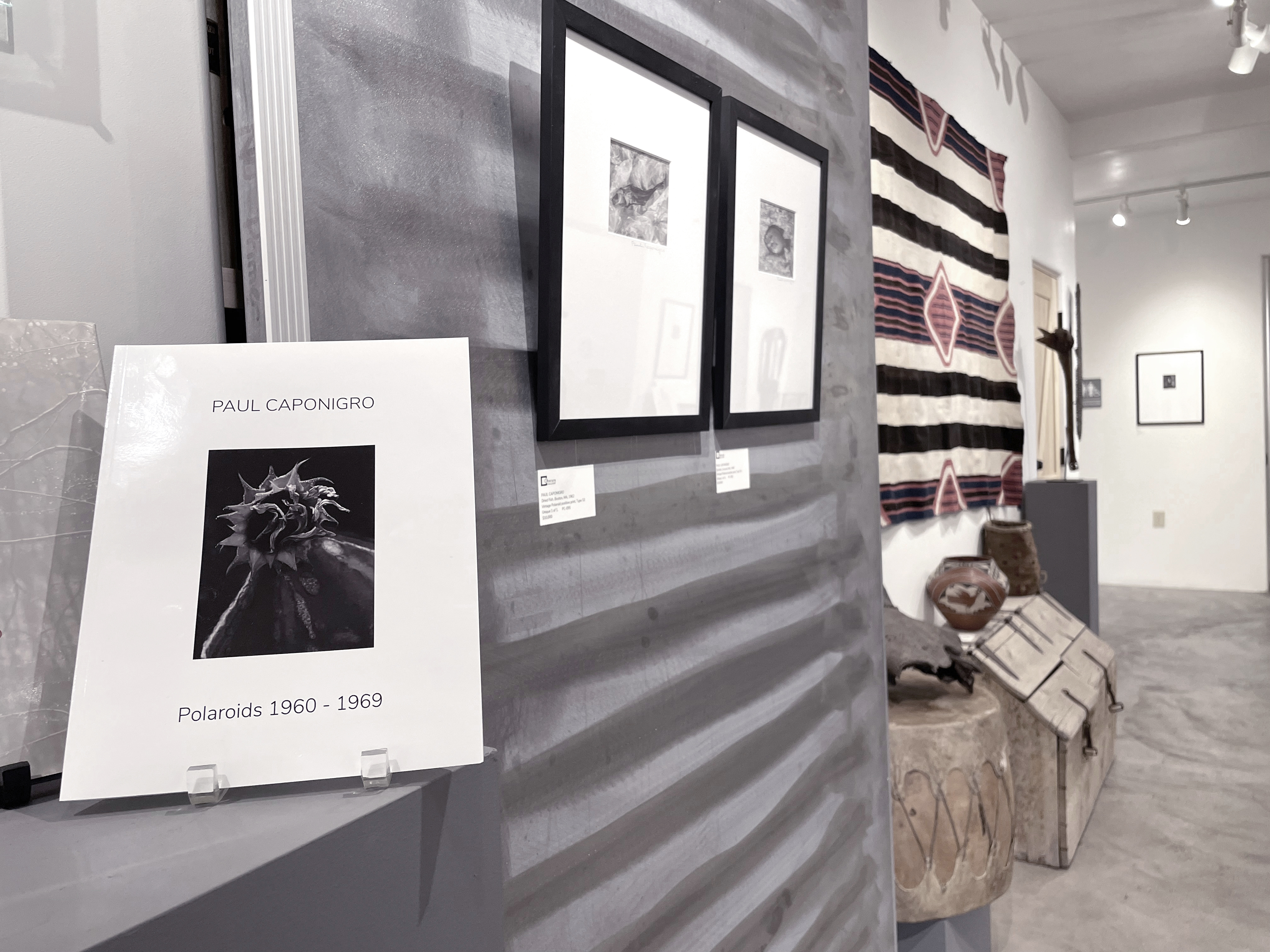 A woman and man sitting on the ground in front of a bench.