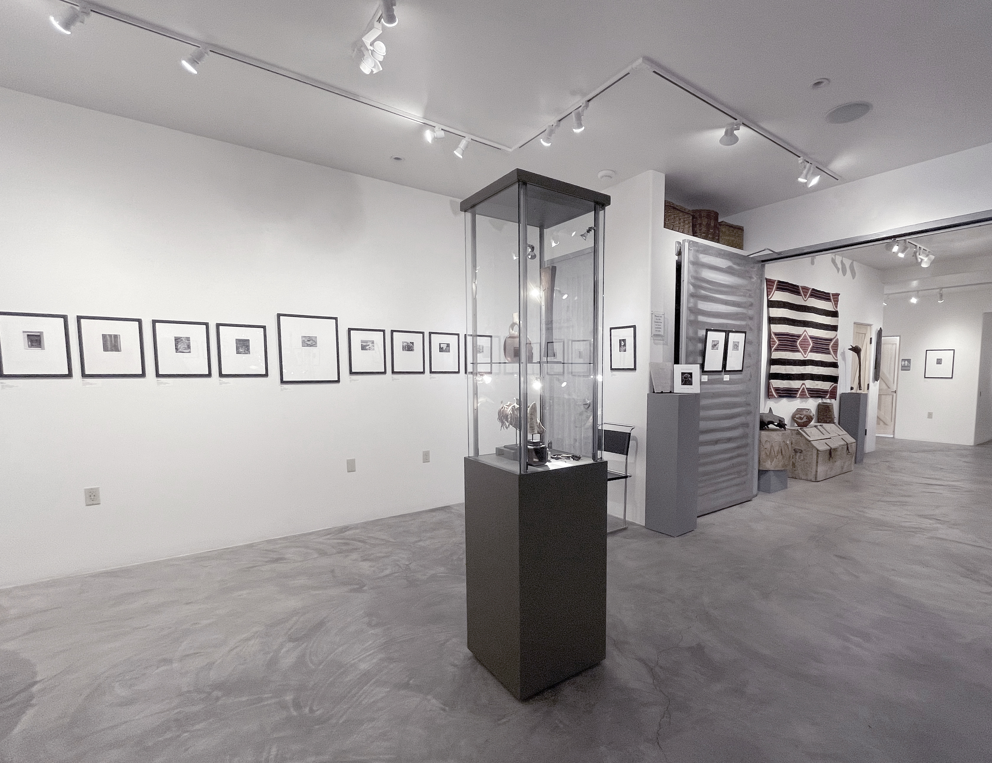A woman and man sitting on the ground in front of a bench.