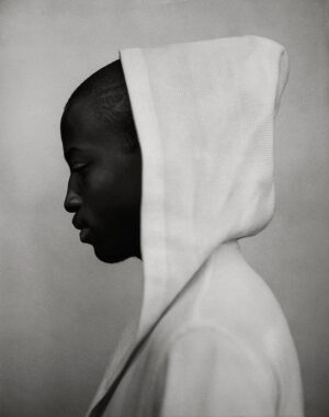 A black and white photo of a person wearing a hooded sweatshirt.