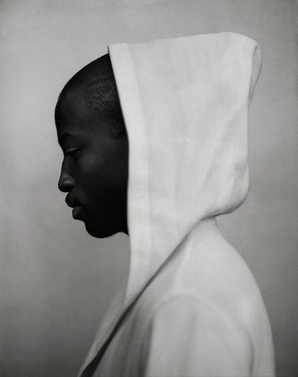 A black and white photo of a person wearing a hooded sweatshirt.