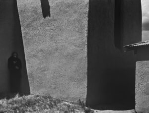 A black and white photo of a person standing in front of a wall.