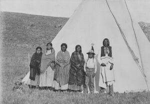 A group of people standing around a teepee.