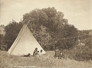 A group of people sitting around in front of a tent.