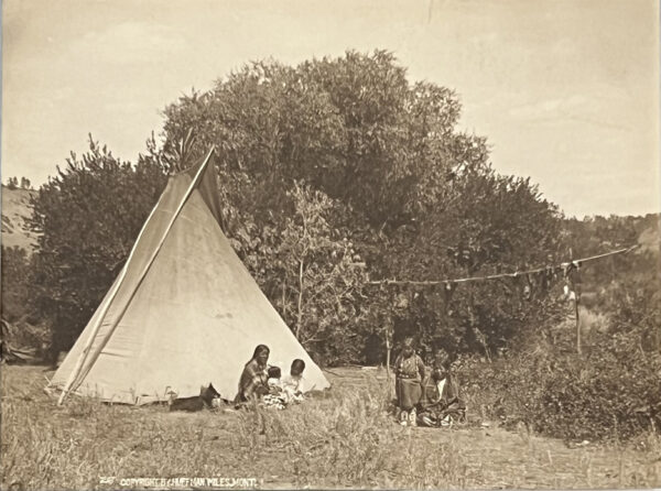 A group of people sitting around in front of a tent.