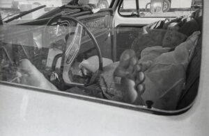 A man 's foot is reflected in the side mirror of his car.