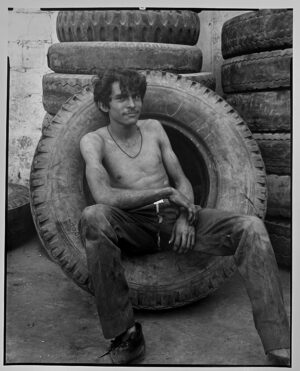 A man sitting in an old tire on the ground.