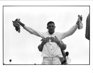 A man holding two pairs of shoes in his arms.