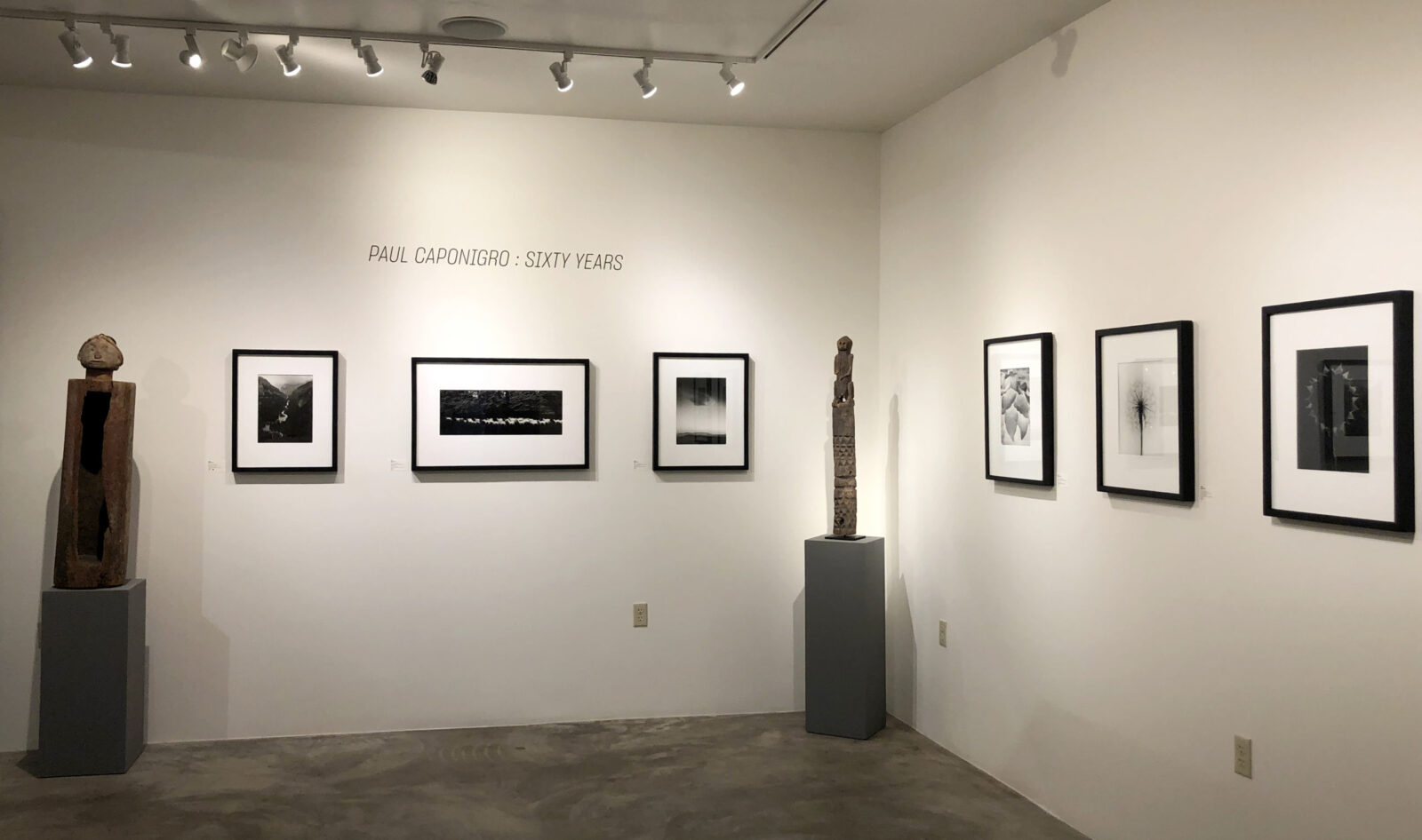 A woman and man sitting on the ground in front of a bench.