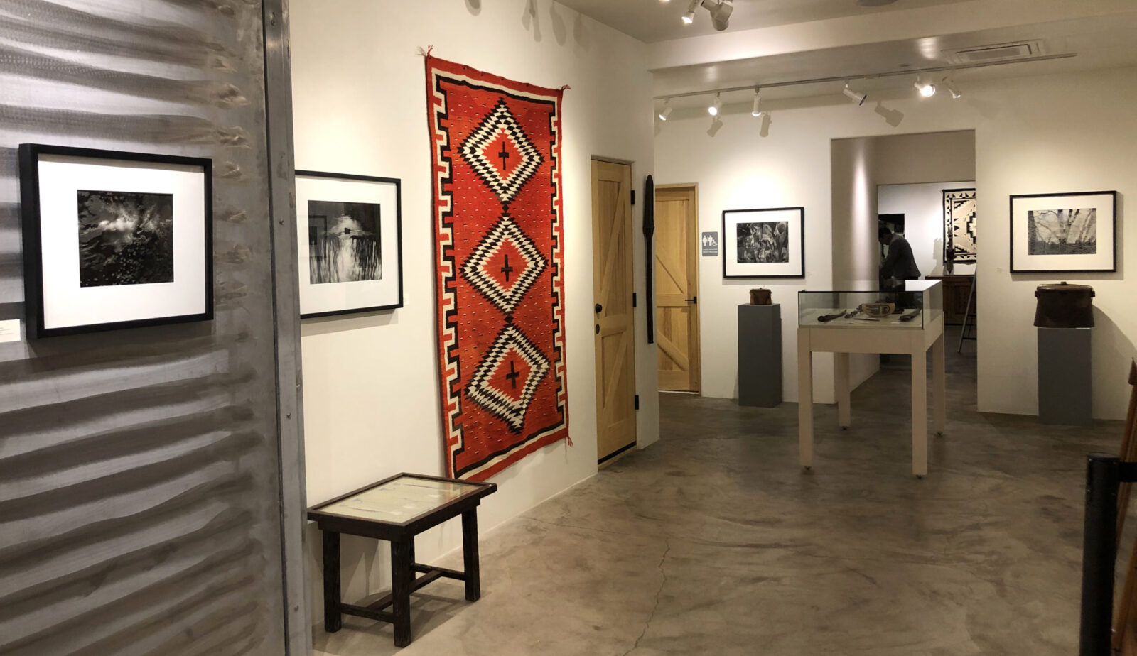 A woman and man sitting on the ground in front of a bench.