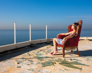 A man and woman sitting on the side of a chair.
