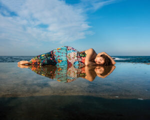 A woman laying on the beach in front of water.