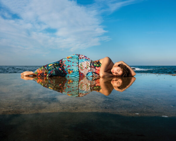 A woman laying on the beach in front of water.