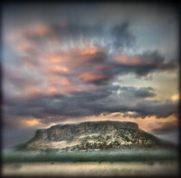 A mountain with clouds in the sky above it
