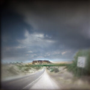 A blurry photo of a road with clouds in the background.