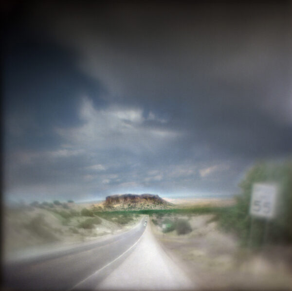 A blurry photo of a road with clouds in the background.
