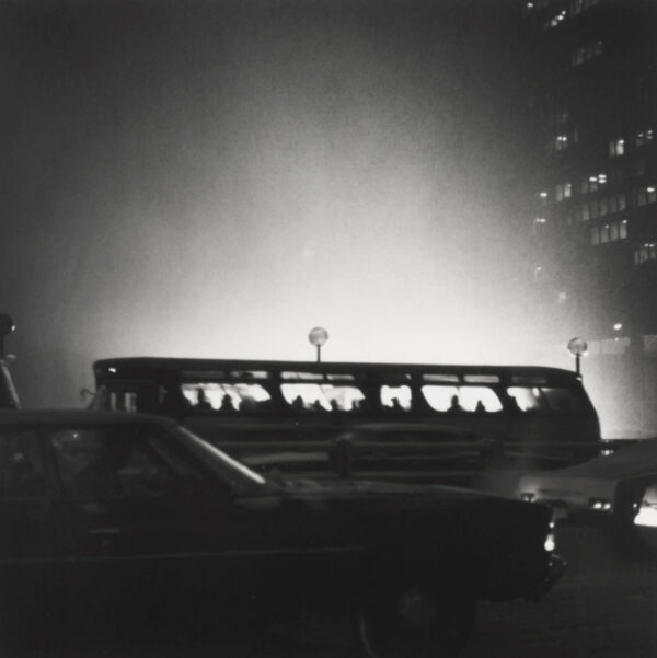 A bus is driving down the street at night.