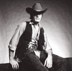A man in cowboy hat sitting on the ground.