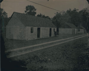 A black and white photo of houses on the side of a road.
