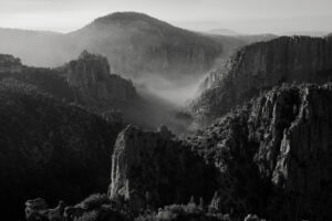 A black and white photo of mountains with fog