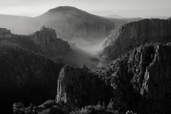 A black and white photo of mountains with fog