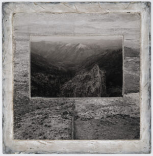 A black and white photo of mountains with trees.