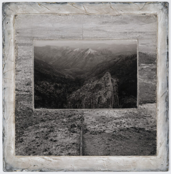 A black and white photo of mountains with trees.