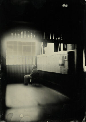 A man sitting on the bench in front of a window.